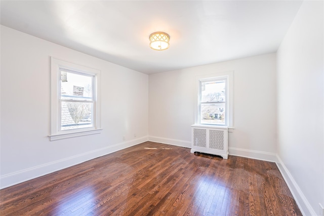 unfurnished room with a healthy amount of sunlight, baseboards, radiator heating unit, and dark wood-type flooring
