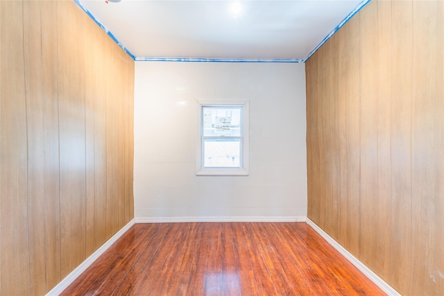 unfurnished room with baseboards and hardwood / wood-style flooring