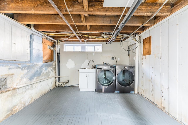 basement featuring a sink, hardwood / wood-style flooring, and washing machine and clothes dryer