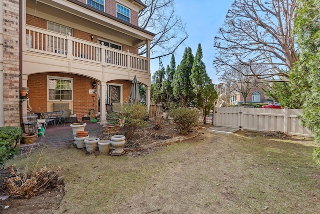 view of yard featuring a patio, a balcony, and fence