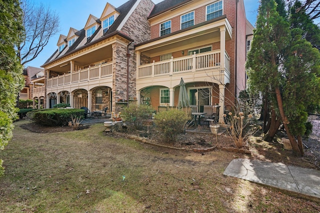 rear view of house with a patio, brick siding, and stone siding