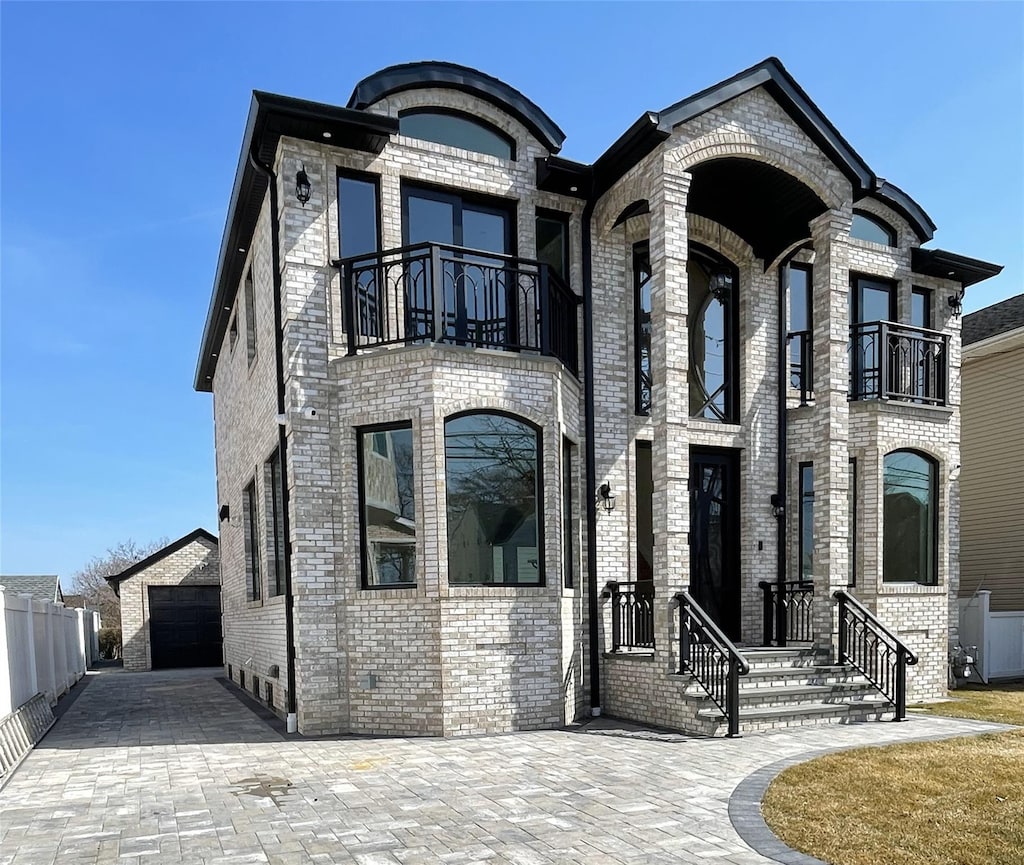 view of front of property featuring an outbuilding, a balcony, and brick siding