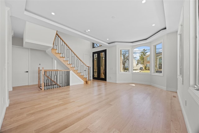 48 Moore St, New Hyde Park, NY 11040 - unfurnished living room featuring a tray ceiling, light wood-style flooring, recessed lighting, and stairway