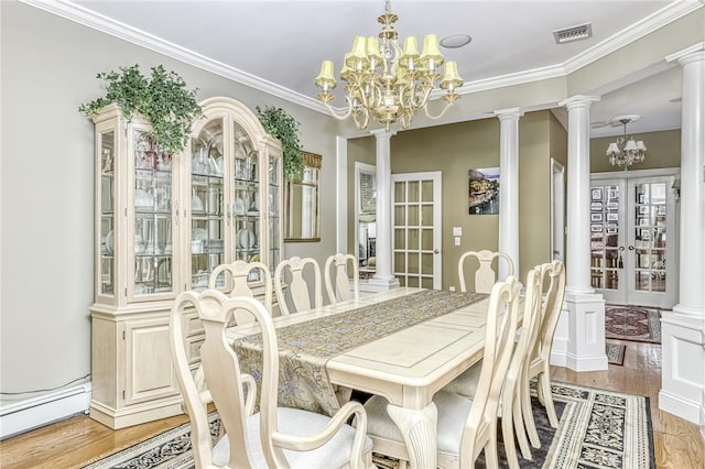 dining area with visible vents, light wood-type flooring, ornamental molding, an inviting chandelier, and ornate columns