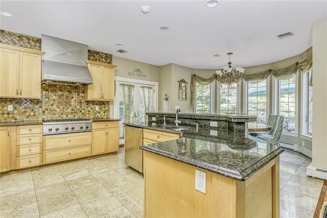 kitchen with light brown cabinetry, appliances with stainless steel finishes, wall chimney range hood, and a sink