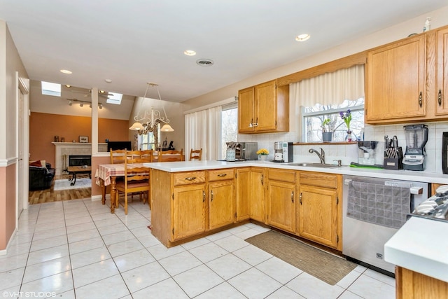 kitchen featuring a sink, backsplash, a peninsula, light countertops, and dishwasher