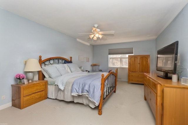 bedroom featuring light colored carpet, a ceiling fan, and baseboards