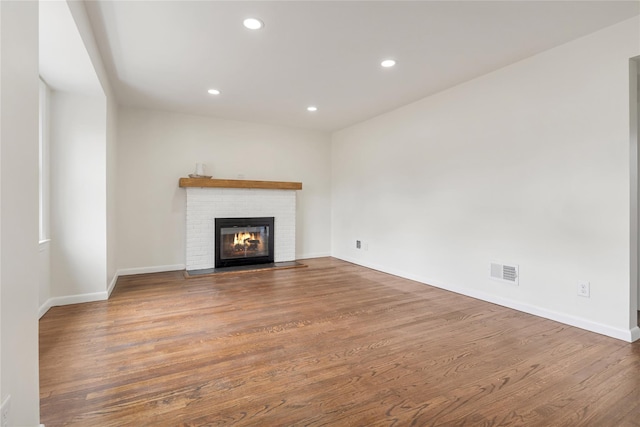 unfurnished living room with visible vents, wood finished floors, recessed lighting, a fireplace, and baseboards