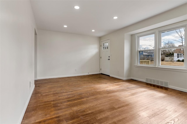 empty room featuring recessed lighting, visible vents, baseboards, and wood finished floors