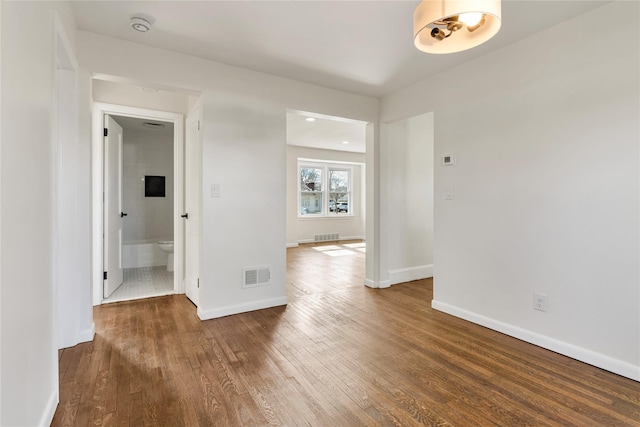 spare room featuring wood finished floors, visible vents, and baseboards