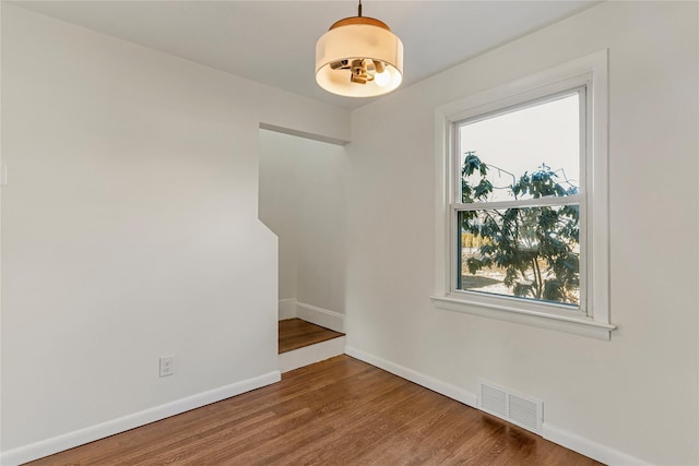 empty room with wood finished floors, visible vents, and baseboards