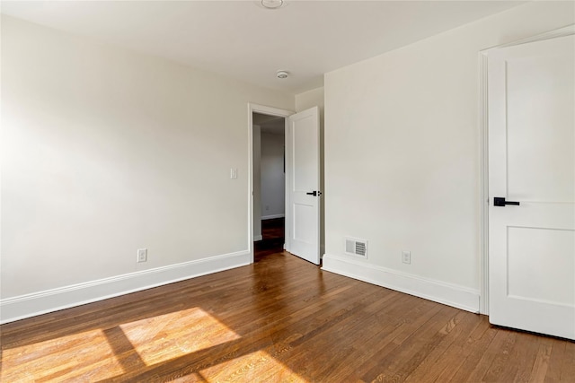 spare room featuring visible vents, baseboards, and wood finished floors