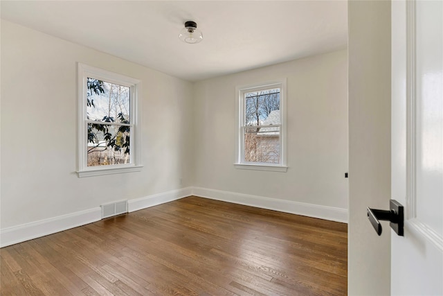 unfurnished room featuring visible vents, baseboards, and hardwood / wood-style flooring