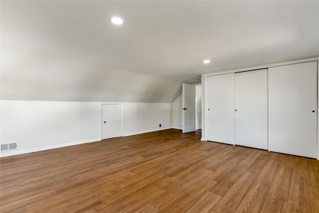 additional living space featuring wood finished floors, visible vents, baseboards, lofted ceiling, and recessed lighting