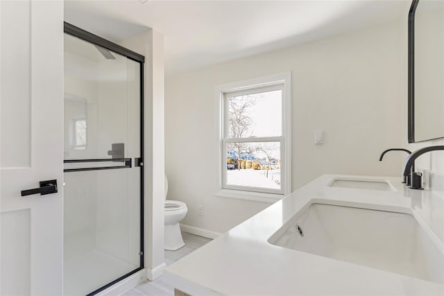 full bathroom featuring a sink, a stall shower, toilet, and double vanity