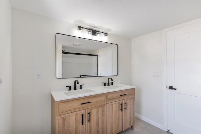 full bathroom with a sink, visible vents, baseboards, and double vanity