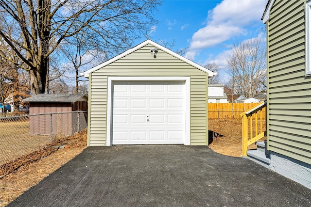 detached garage with aphalt driveway and fence