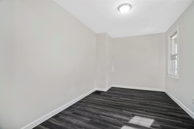 empty room featuring baseboards and dark wood-style floors