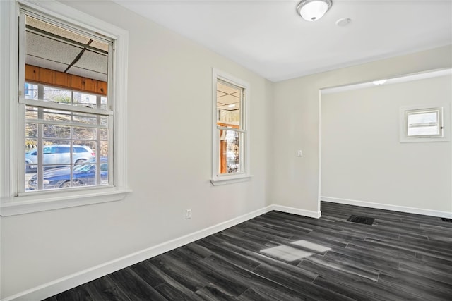 unfurnished room featuring dark wood-style floors, a paneled ceiling, and baseboards