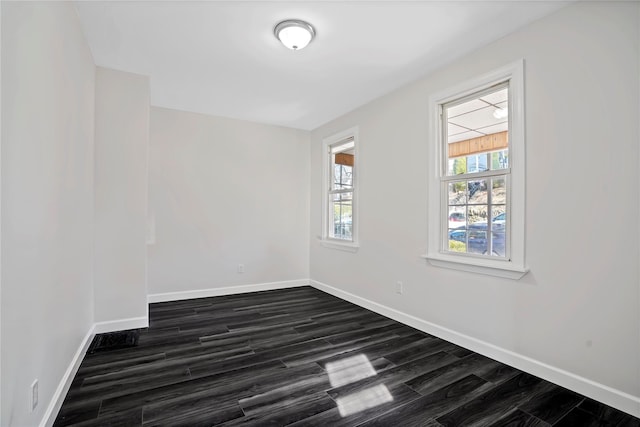 unfurnished room featuring baseboards and dark wood-style flooring