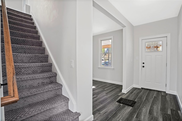 foyer entrance featuring baseboards, dark wood-type flooring, and stairs