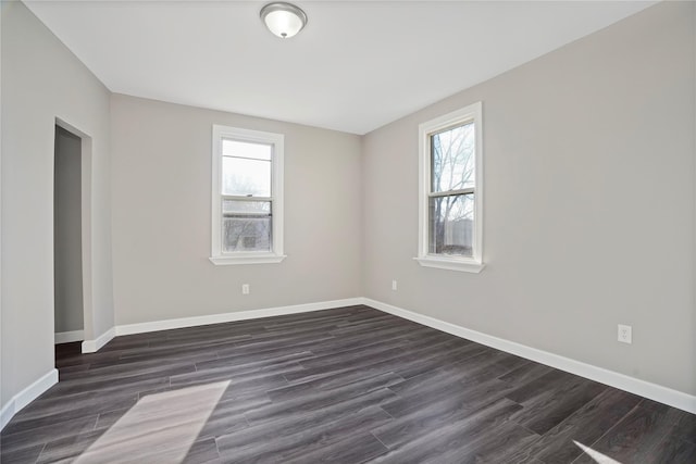 empty room featuring dark wood-style flooring, baseboards, and a wealth of natural light