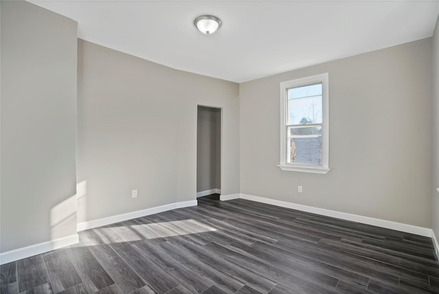 empty room featuring dark wood-style floors and baseboards