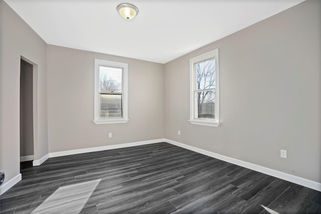 unfurnished room featuring baseboards and dark wood finished floors