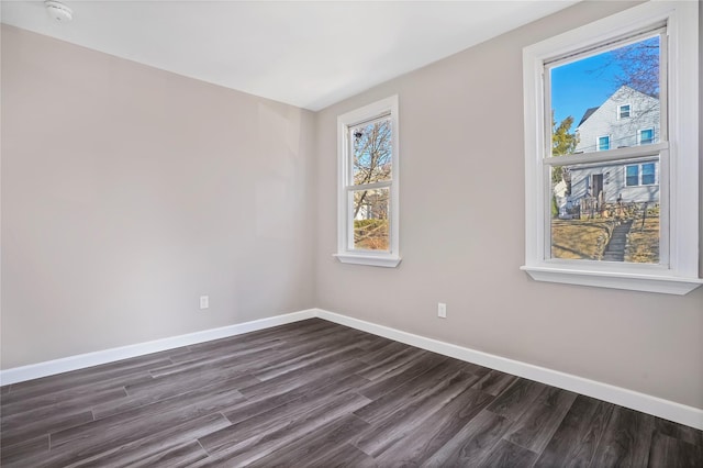 spare room featuring baseboards and dark wood finished floors