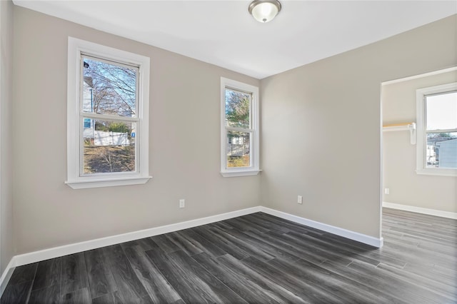 spare room featuring dark wood-type flooring and baseboards