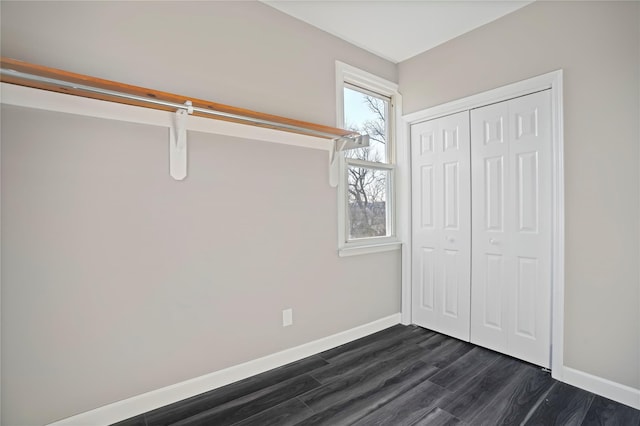 unfurnished bedroom featuring a closet, baseboards, and dark wood-type flooring