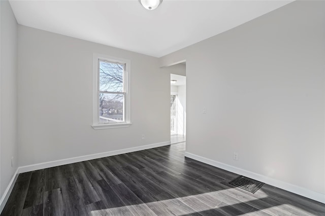 unfurnished room featuring dark wood-type flooring, baseboards, and visible vents