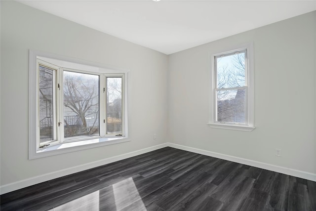 unfurnished room featuring baseboards and dark wood finished floors