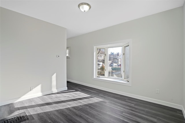 unfurnished room featuring visible vents, baseboards, and dark wood-style flooring