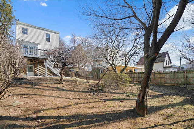 view of yard featuring a wooden deck, stairs, and fence