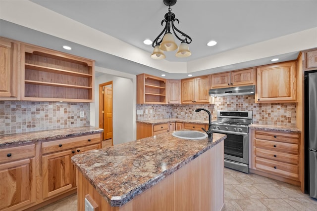 kitchen with light stone countertops, a center island with sink, open shelves, stainless steel appliances, and under cabinet range hood