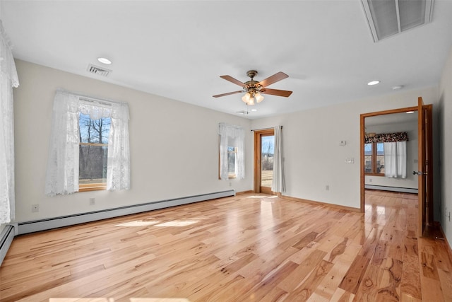 unfurnished room with a baseboard heating unit, visible vents, and light wood finished floors