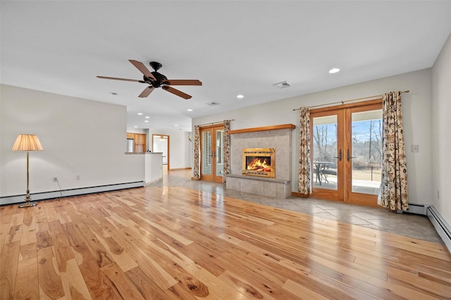 unfurnished living room featuring french doors, baseboard heating, and wood finished floors