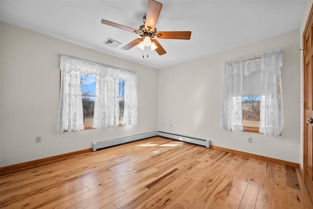 empty room featuring a wealth of natural light, visible vents, a ceiling fan, and light wood finished floors