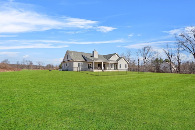 rear view of house featuring a lawn, fence, and a chimney