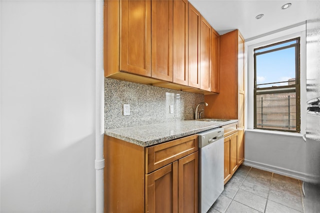 kitchen with brown cabinets, a sink, tasteful backsplash, baseboards, and dishwasher