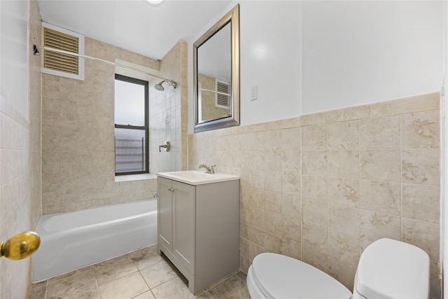 bathroom featuring toilet, shower / tub combination, tile walls, tile patterned flooring, and vanity