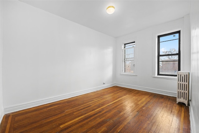 spare room with baseboards, radiator, and hardwood / wood-style flooring