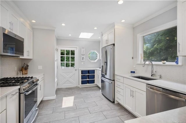 kitchen featuring tasteful backsplash, appliances with stainless steel finishes, a skylight, and a sink