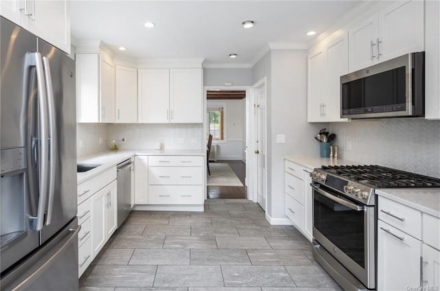 kitchen with ornamental molding, white cabinetry, stainless steel appliances, light countertops, and decorative backsplash