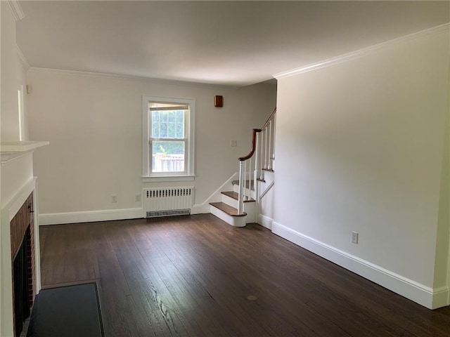 unfurnished living room with dark wood-type flooring, radiator, crown molding, a brick fireplace, and stairs