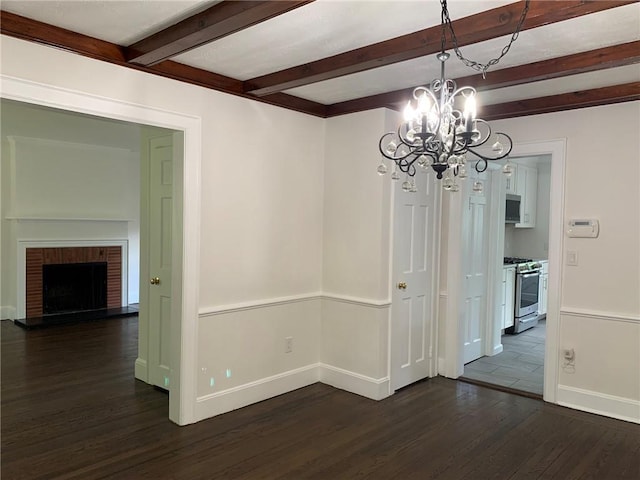 unfurnished dining area with baseboards, dark wood finished floors, beam ceiling, a fireplace, and a chandelier