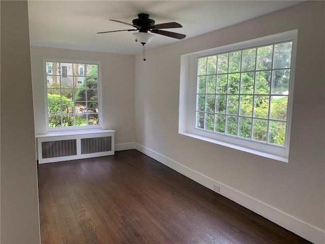 empty room featuring plenty of natural light, ceiling fan, radiator, and baseboards