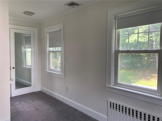 spare room featuring radiator, visible vents, carpet floors, and ornamental molding