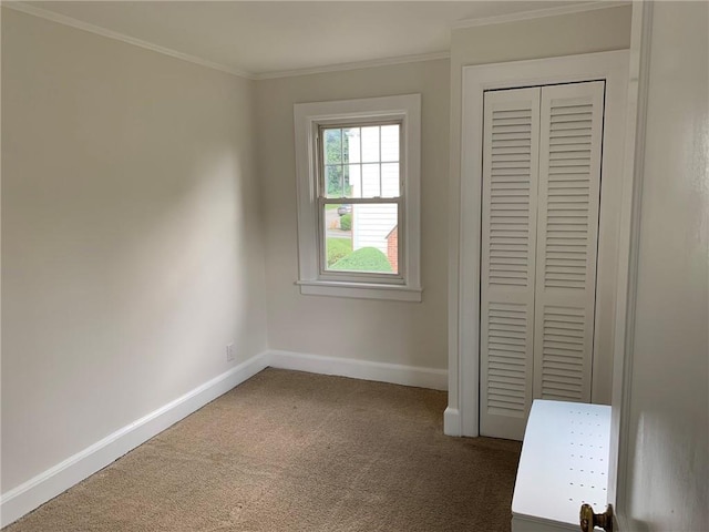 unfurnished bedroom featuring a closet, baseboards, ornamental molding, and carpet flooring